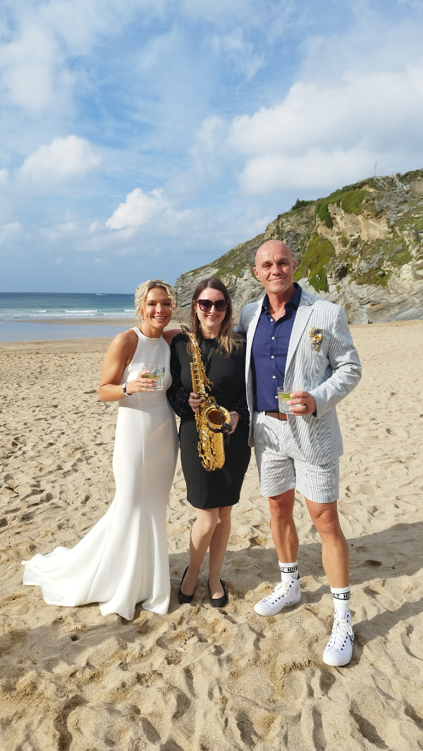 Clare with a bride and groom on the beach as part of her full day live wedding music package